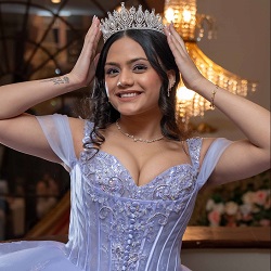 Sweet 16 Portrait in Lavender Gown | The Glorious Memories Smiling young woman wearing a lavender Sweet 16 gown and tiara, posing indoors with her hands on her head.